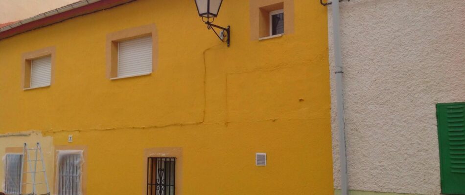 La fachada de una casa pintada de color amarillo oscuro en Ávila